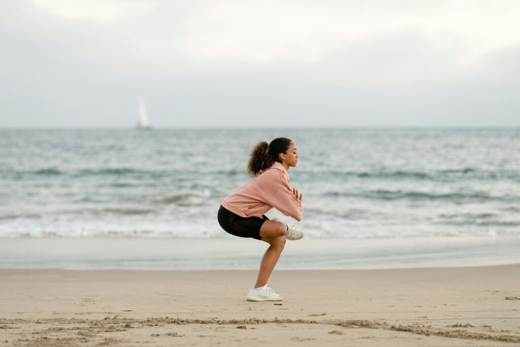 A woman in sportswear is doing yoga on the beach.