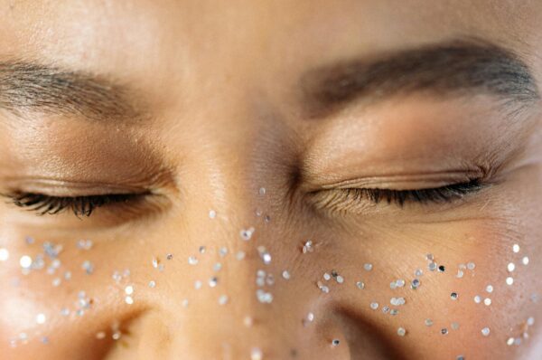 Close up of woman's face wearing silver gems across her nose and cheeks like freckles.